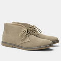 Taupe suede chukka boots featuring a rounded toe, short lace-up front, and contrast panel stitching on a low stacked heel.