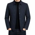 Men's navy quilted button-front jacket with a classic collar, diamond quilted front panel, and long sleeves layered over a black shirt