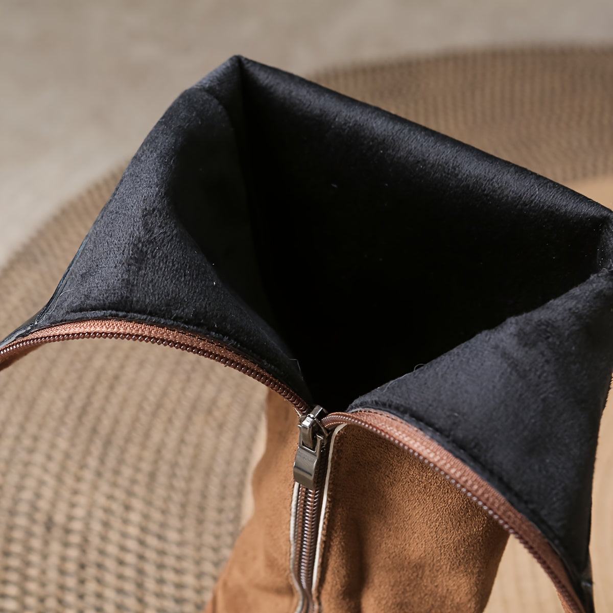 Knee high riding boot in tan brushed matte nap with a black interior lining and exposed metal side zipper.