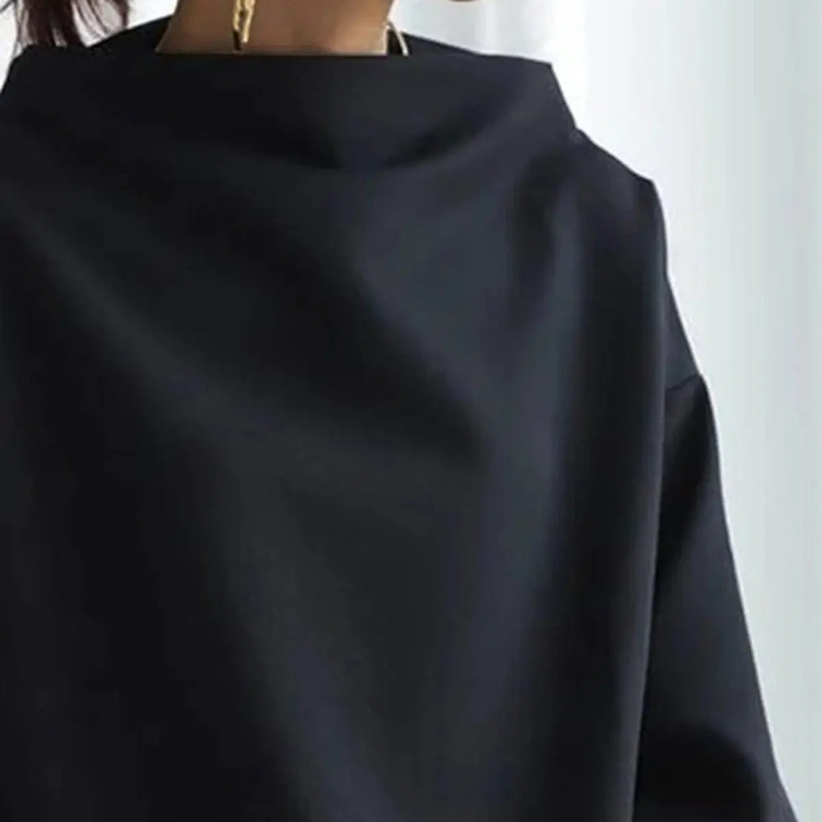 Close-up of a black oversized mock neck sweatshirt highlighting the relaxed neckline and smooth fabric texture.