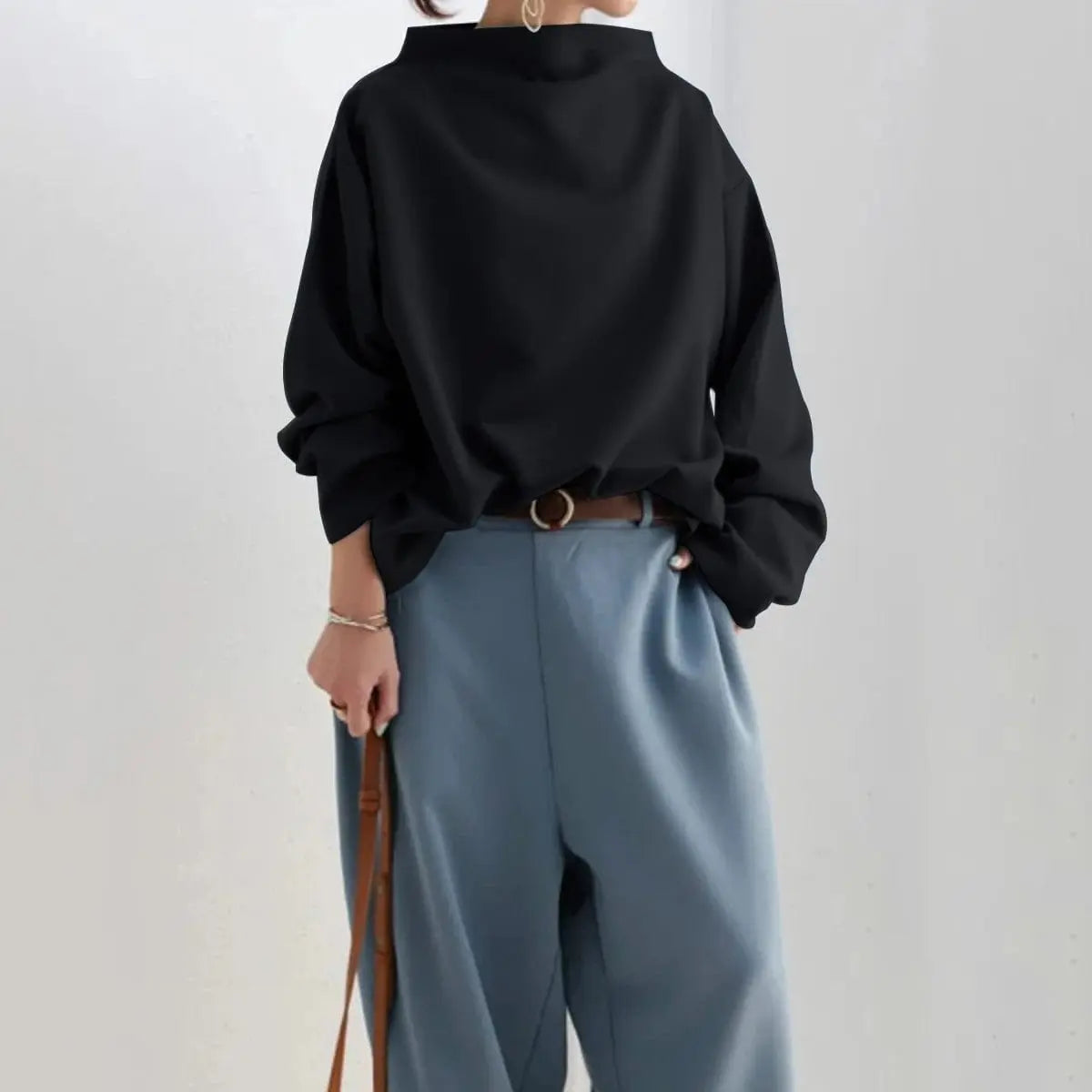 Black oversized mock neck sweatshirt with dropped shoulders, paired with gray wide-leg trousers for a modern casual outfit.
