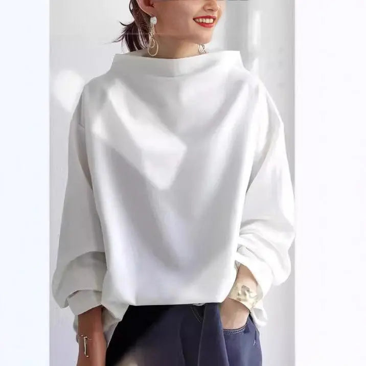 White oversized mock neck sweatshirt with dropped shoulders and ribbed cuffs, paired with neutral trousers for a minimalist casual look.