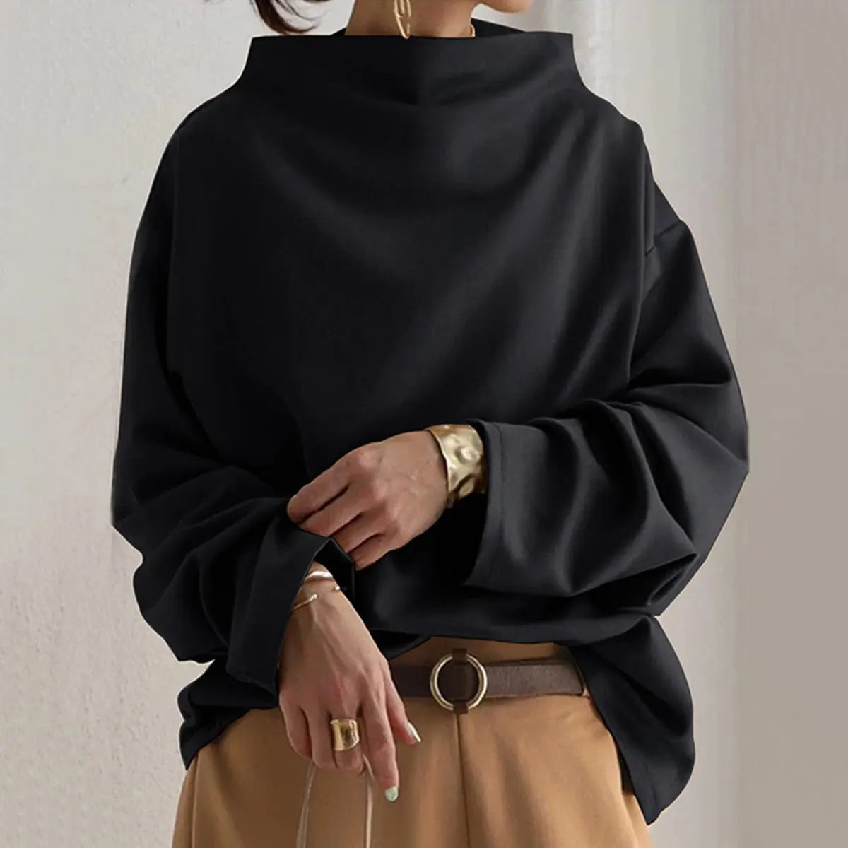 Black oversized mock neck sweatshirt with dropped shoulders and long sleeves, styled with beige trousers for a relaxed casual look.