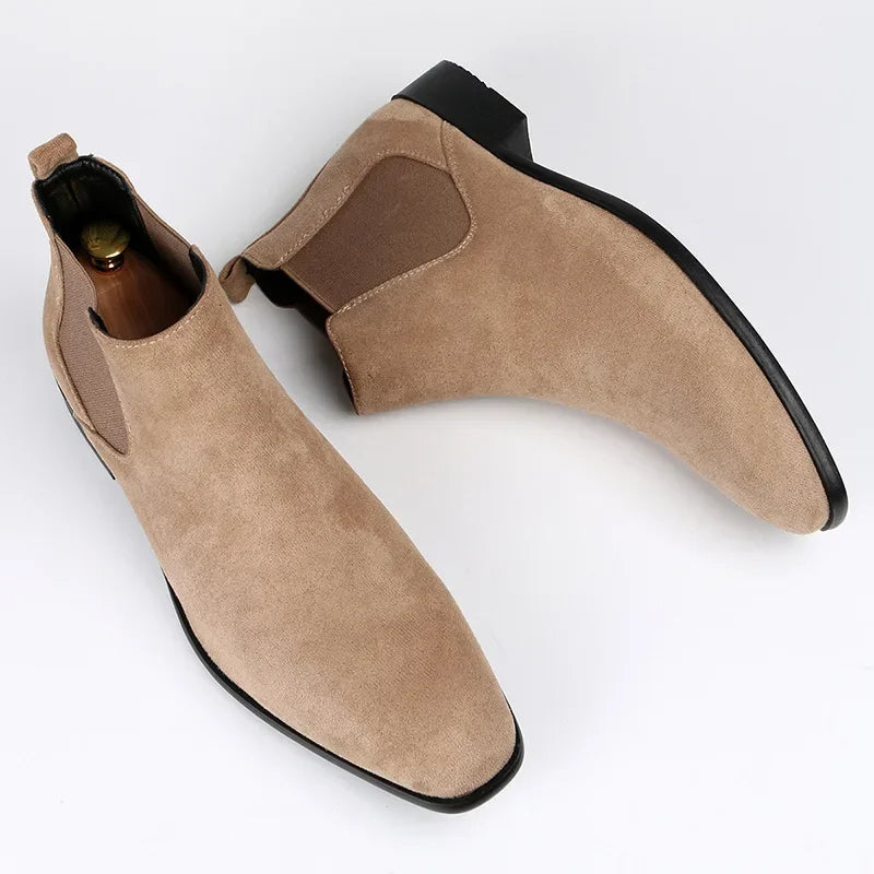 Tan suede Chelsea boots with a modern square toe, elastic side panels, and a low block heel on a white background.