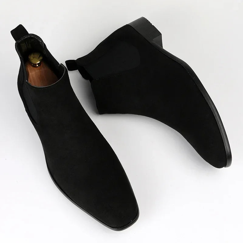 Black suede Chelsea boots with a modern square toe, elastic side panels, and a low block heel on a white background.
