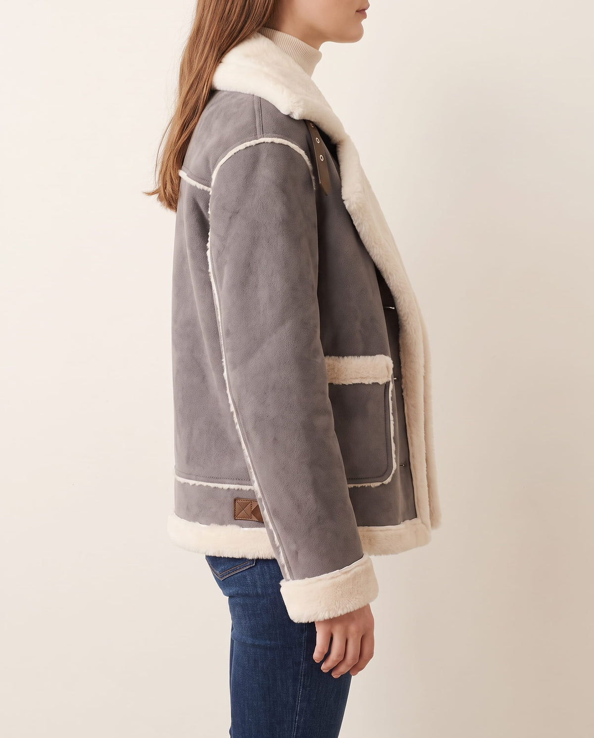 Gray shearling aviator jacket with a plush cream collar, buckle shoulder straps, and trimmed cuffs in a relaxed fit.