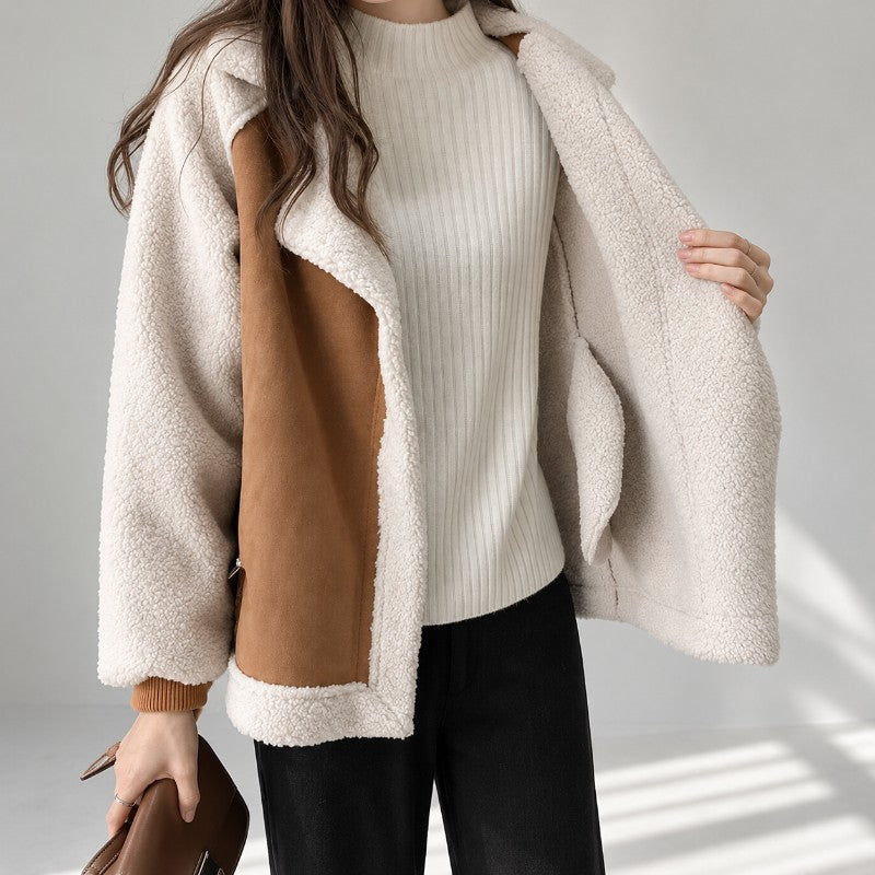 A woman wearing a brown sherpa suede aviator jacket with an oversized lapel and zip front, shown with the jacket open