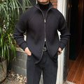 Black ribbed cotton-blend zip-up cardigan with a stand collar and slim-fit silhouette worn over a black turtleneck.