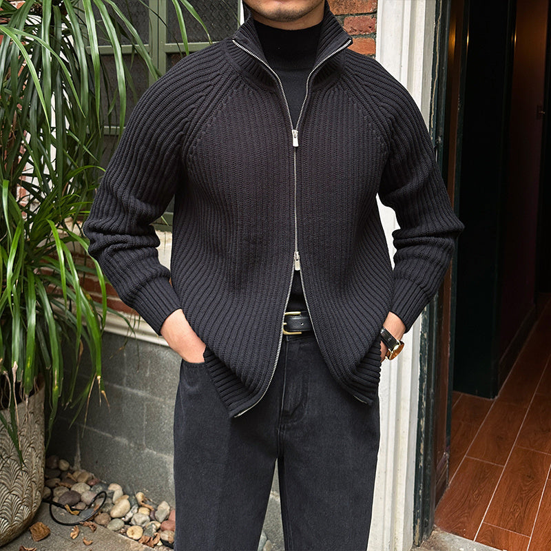 Black ribbed cotton-blend zip-up cardigan with a stand collar and slim-fit silhouette worn over a black turtleneck.