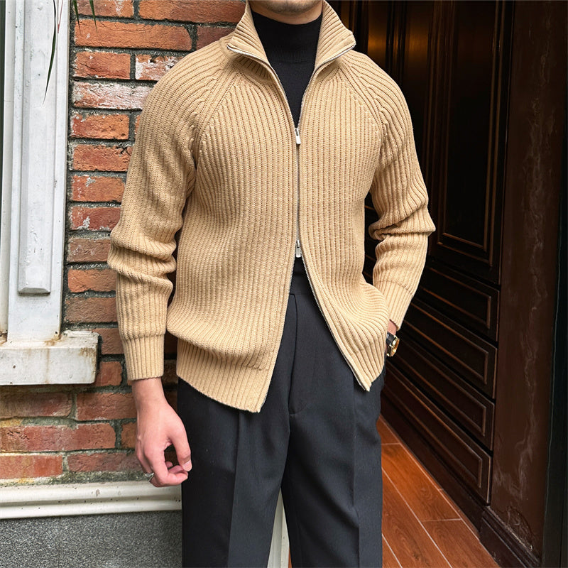 Beige ribbed cotton-blend zip-up cardigan with a stand collar, worn over a black turtleneck and tailored trousers.