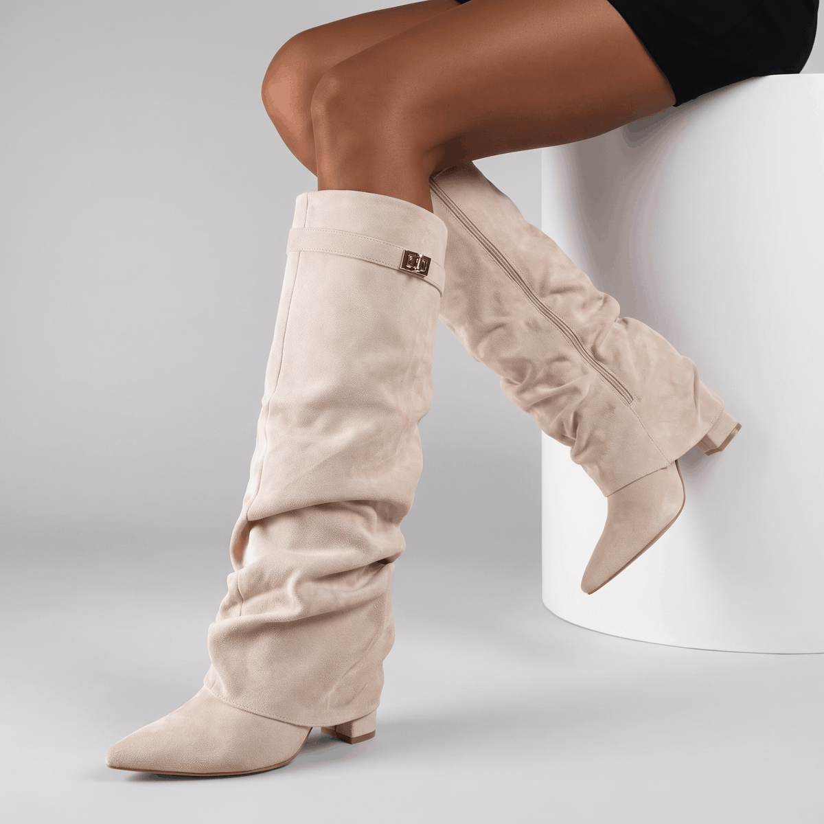Close-up of beige slouchy fold-over boots showing the pointed toe and stacked heel