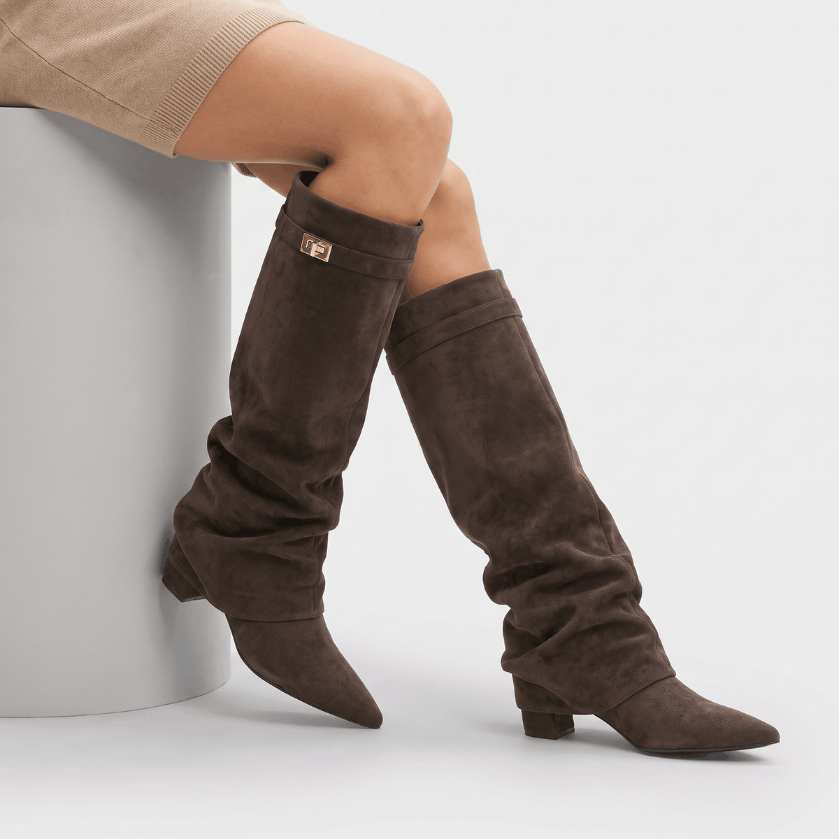 Dark brown slouchy fold-over boots worn by a model, showing the pointed toe and low heel