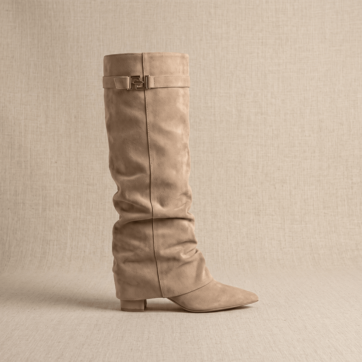 Beige slouchy fold-over boots shown from the side with pointed toes and strap detail