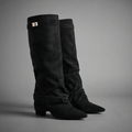 Black slouchy fold-over knee-high boots with pointed toes and strap detail