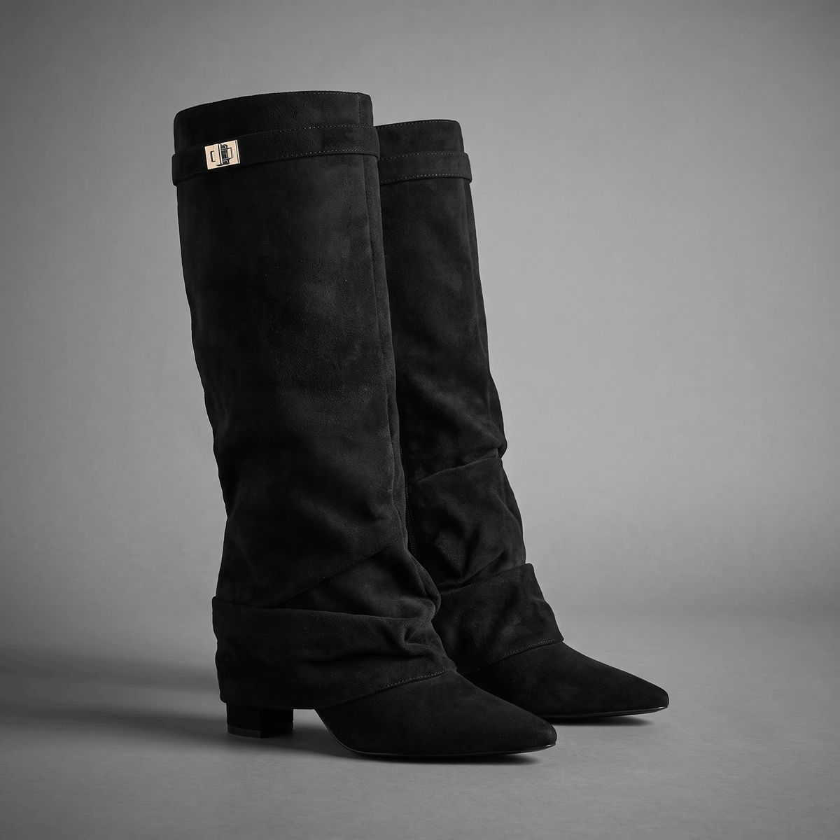 Black slouchy fold-over knee-high boots with pointed toes and strap detail
