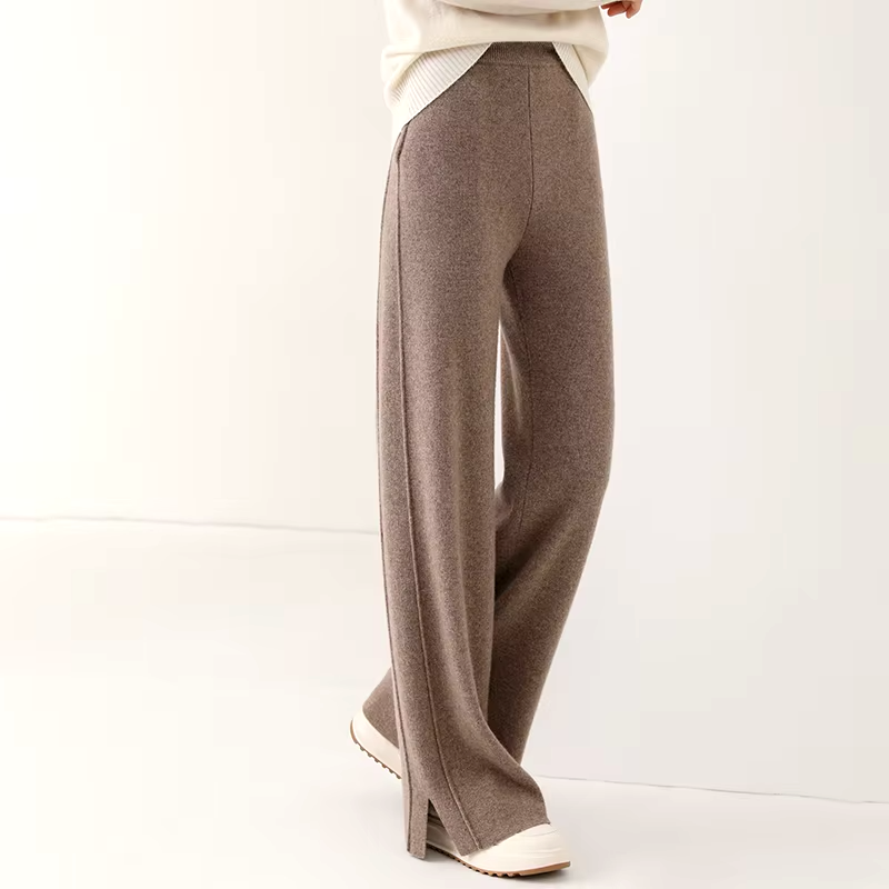 Side view of a model wearing brown straight-leg knit wool trousers with slit hem detail.