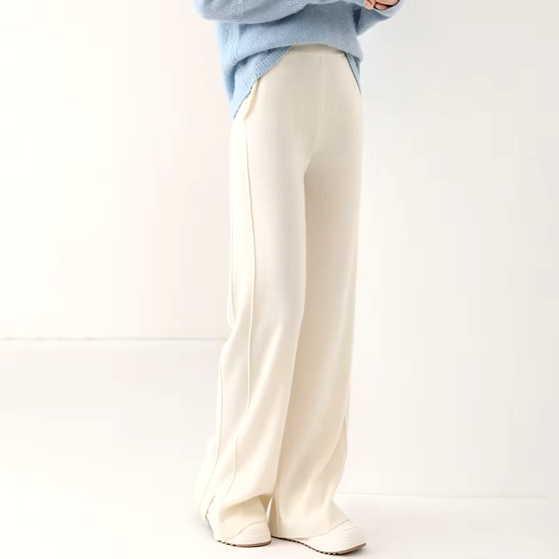 Front view of a model wearing off-white straight-leg wool knit trousers with elastic waistband and slit hems.