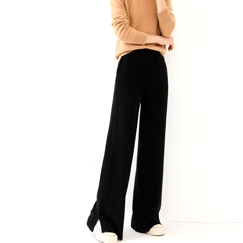Side view of a model wearing black straight-leg wool knit pants with side slit hems and elastic waistband, styled with an orange sweater.