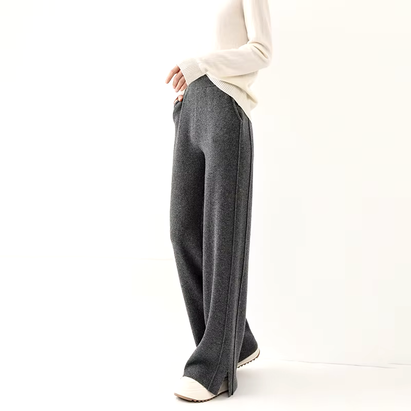 Side view of a model wearing dark gray straight-leg wool knit trousers showcasing the slit hem.