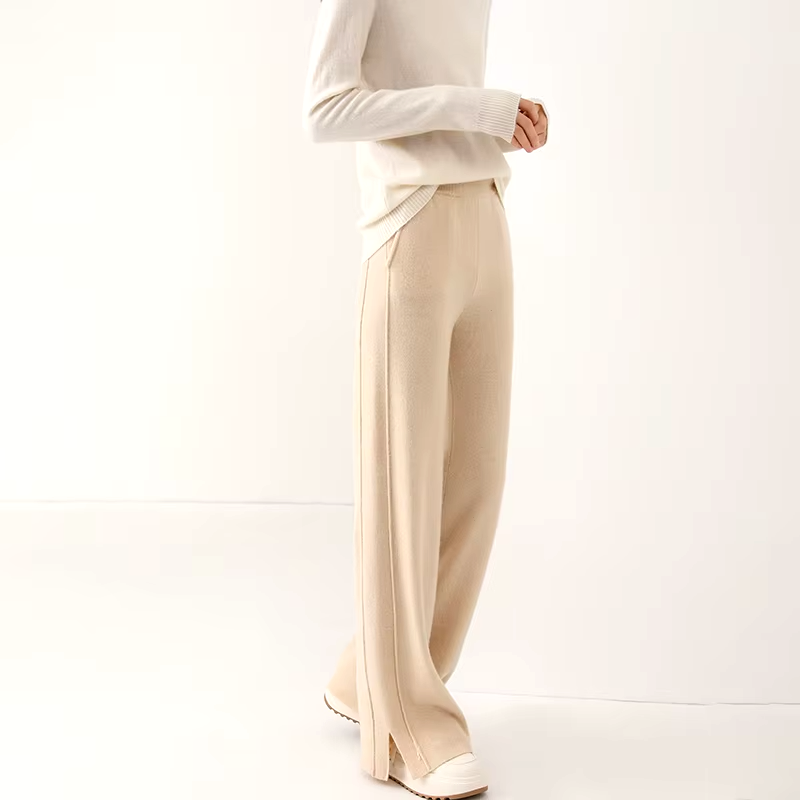 Full-length view of a model wearing light beige straight-leg knit wool trousers paired with a white long-sleeve sweater.