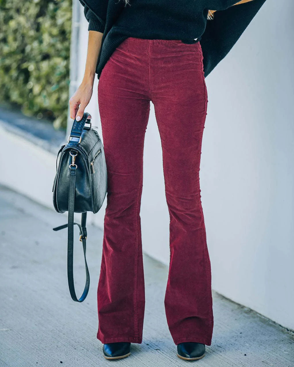 Burgundy high-rise flare pants in ribbed stretch corduroy with a smooth flat-front fit, styled with black boots.