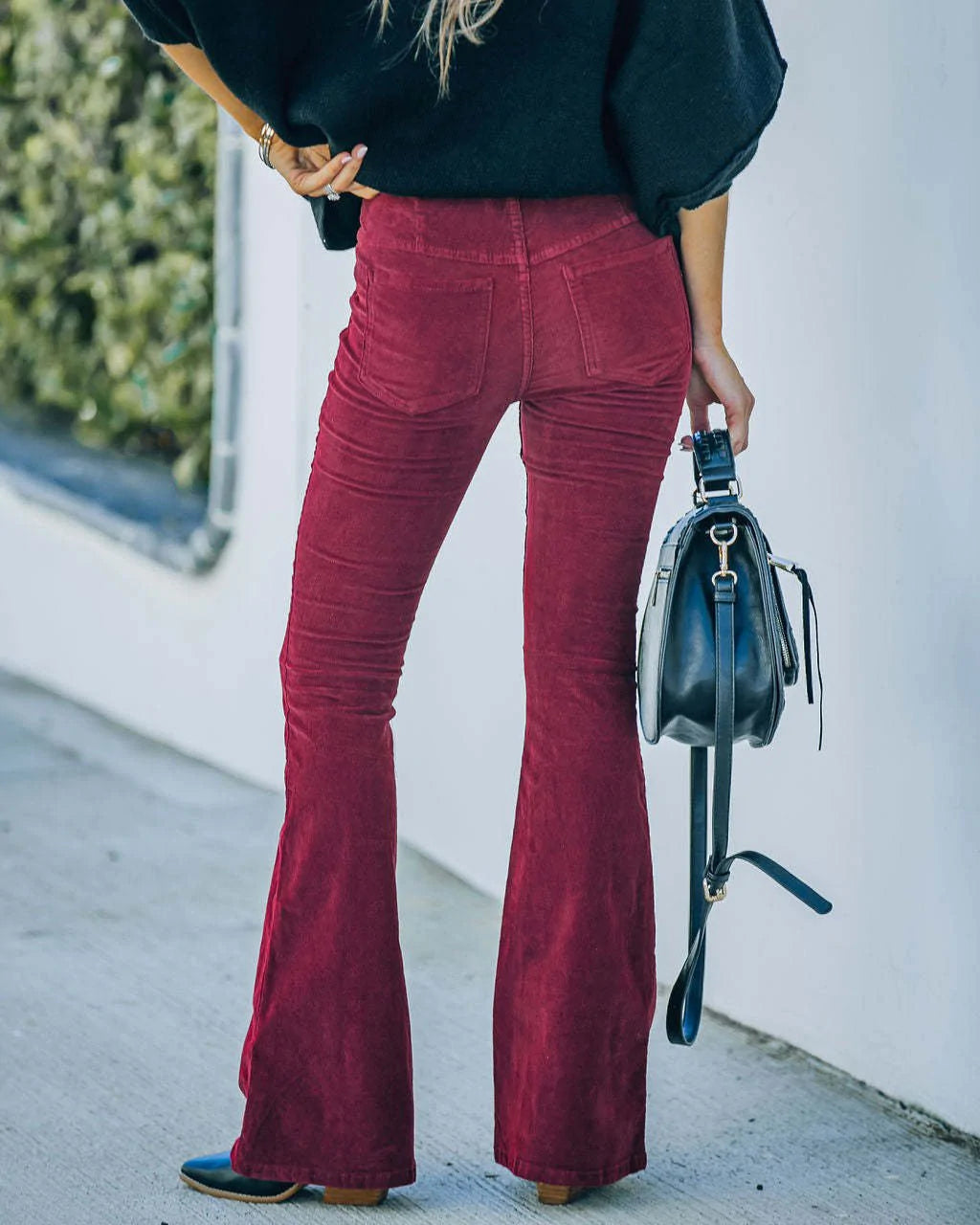 High-rise burgundy corduroy flare pants with a fitted hip, back pockets, and fine vertical ribbing texture.