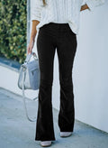 Black high-rise flare pants in ribbed corduroy with a smooth flat front, styled with a white cable knit sweater.