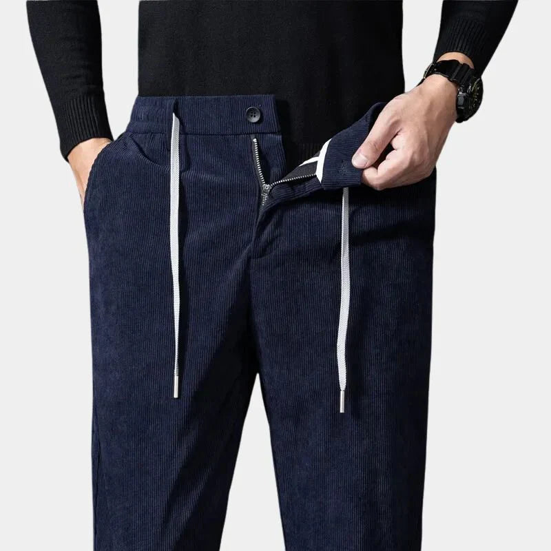 Navy blue stretch corduroy pants featuring a straight-leg cut, elastic drawstring waist, and a functional zip-fly closure.