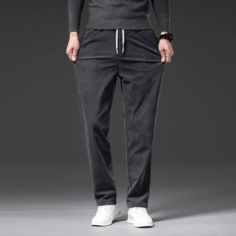 Charcoal gray stretch corduroy pants with a straight-leg cut, elastic drawstring waist, and ribbed texture.