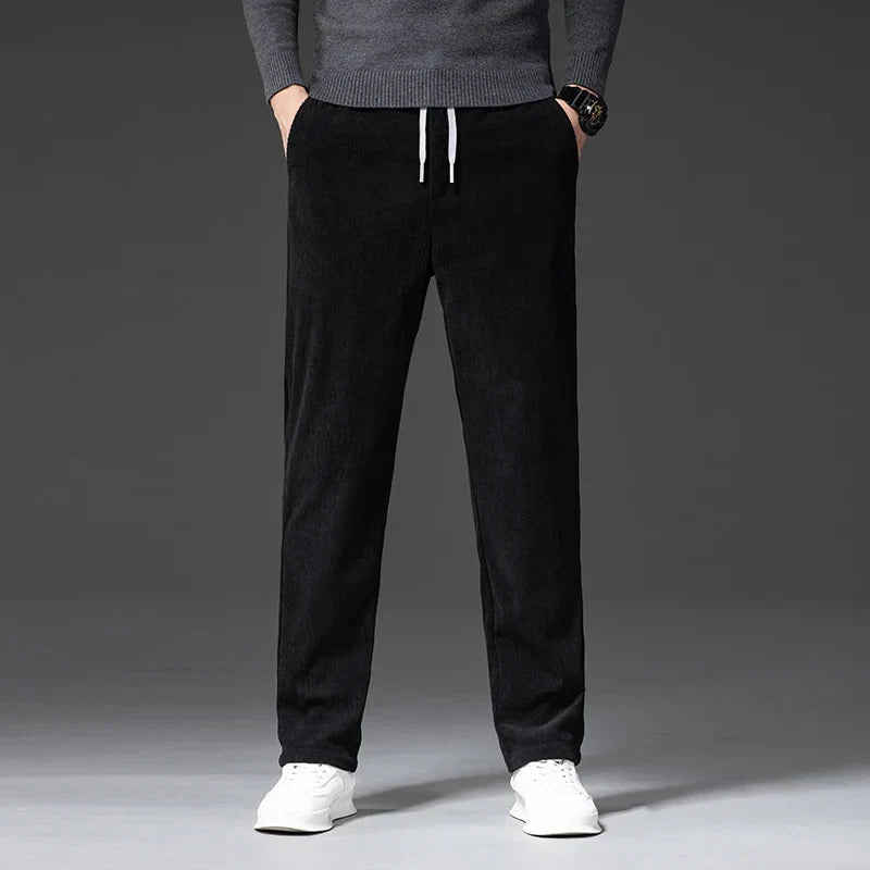 Black stretch corduroy pants featuring a straight-leg cut, elastic drawstring waist, and ribbed texture.