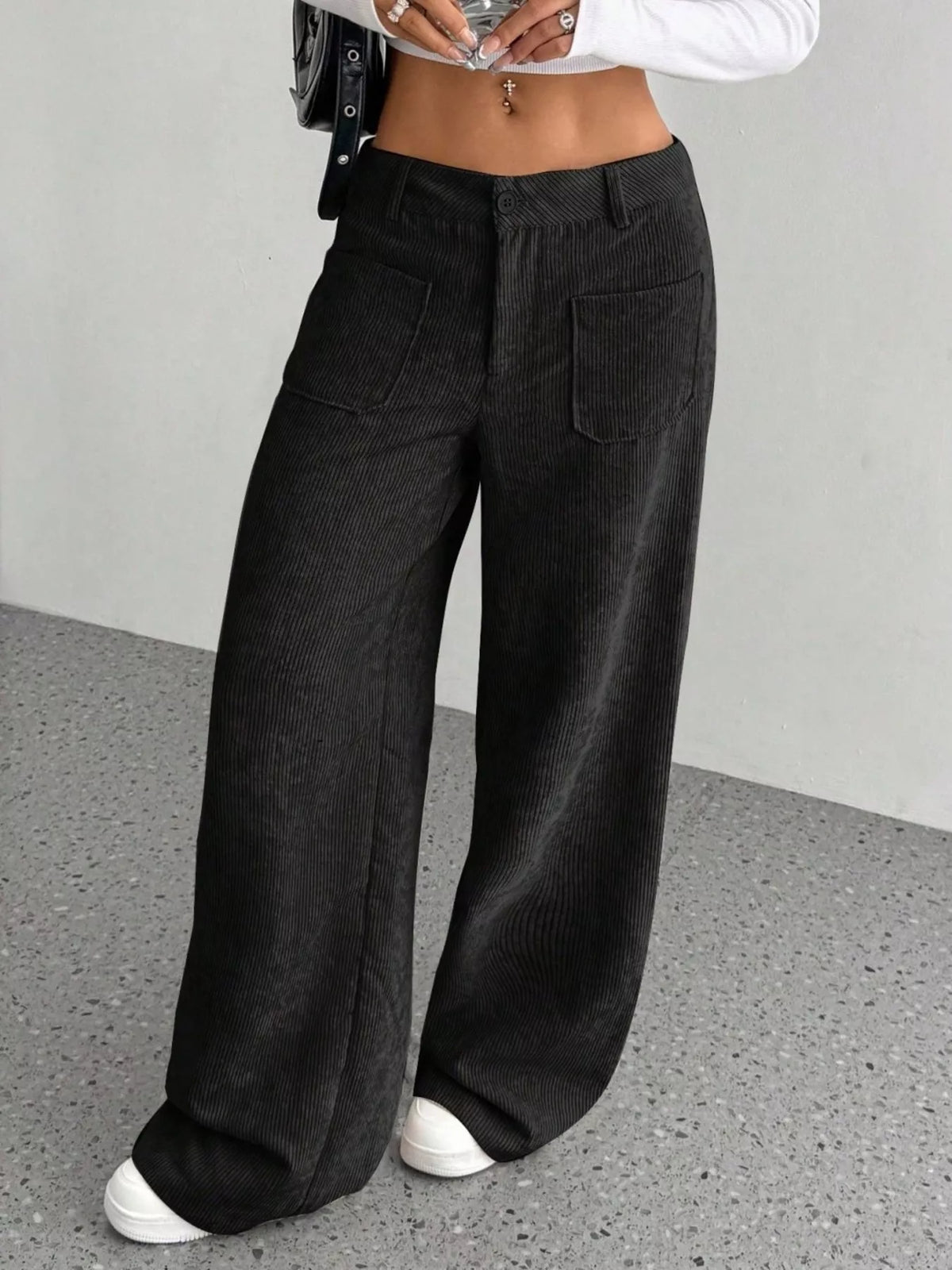 Black stretch corduroy wide-leg pants featuring front patch pockets, a button-zip fly, and a relaxed, floor-length fit.