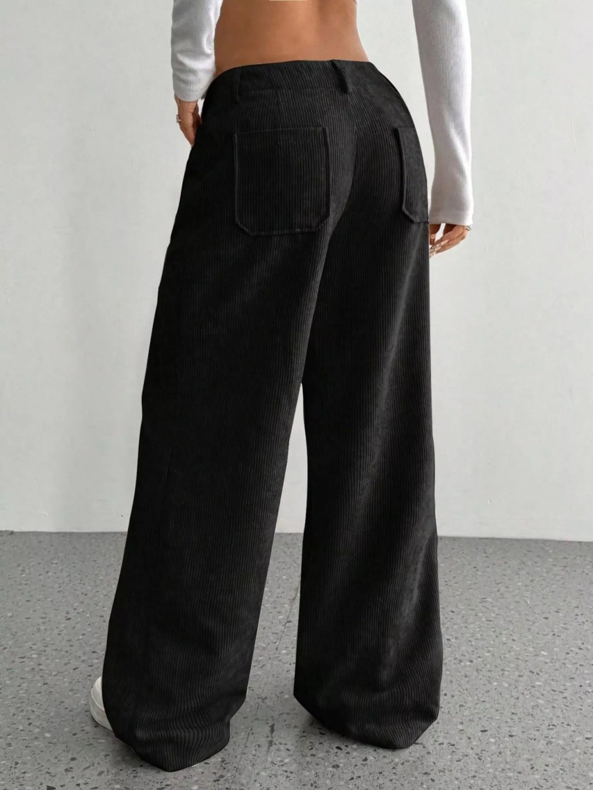 Black wide-leg corduroy pants featuring a mid-rise waist, belt loops, and back patch pockets in a soft ribbed texture.