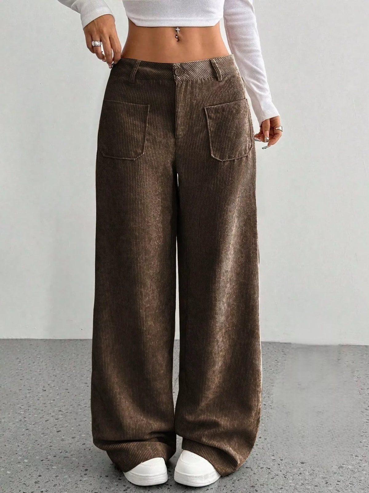 Brown wide-leg corduroy pants featuring front patch pockets, a button-zip fly, and a relaxed mid-rise fit.