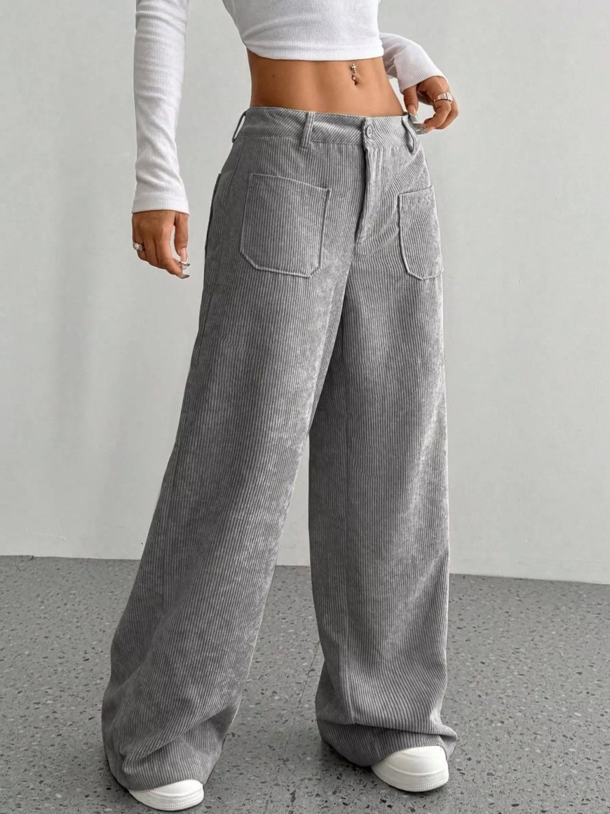 Gray wide-leg corduroy pants featuring front patch pockets, a button-zip fly, and a relaxed, floor-length fit.