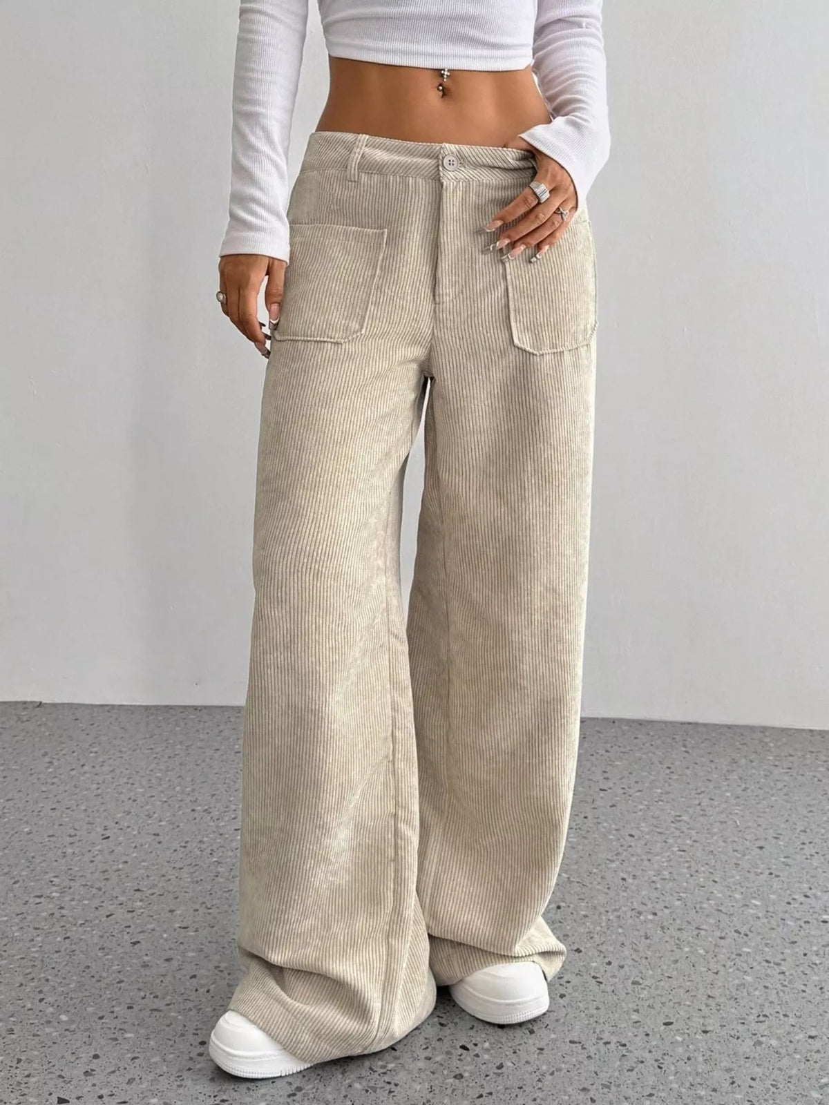 Beige stretch corduroy wide-leg pants featuring front patch pockets, a button-zip fly, and a relaxed, floor-length fit.