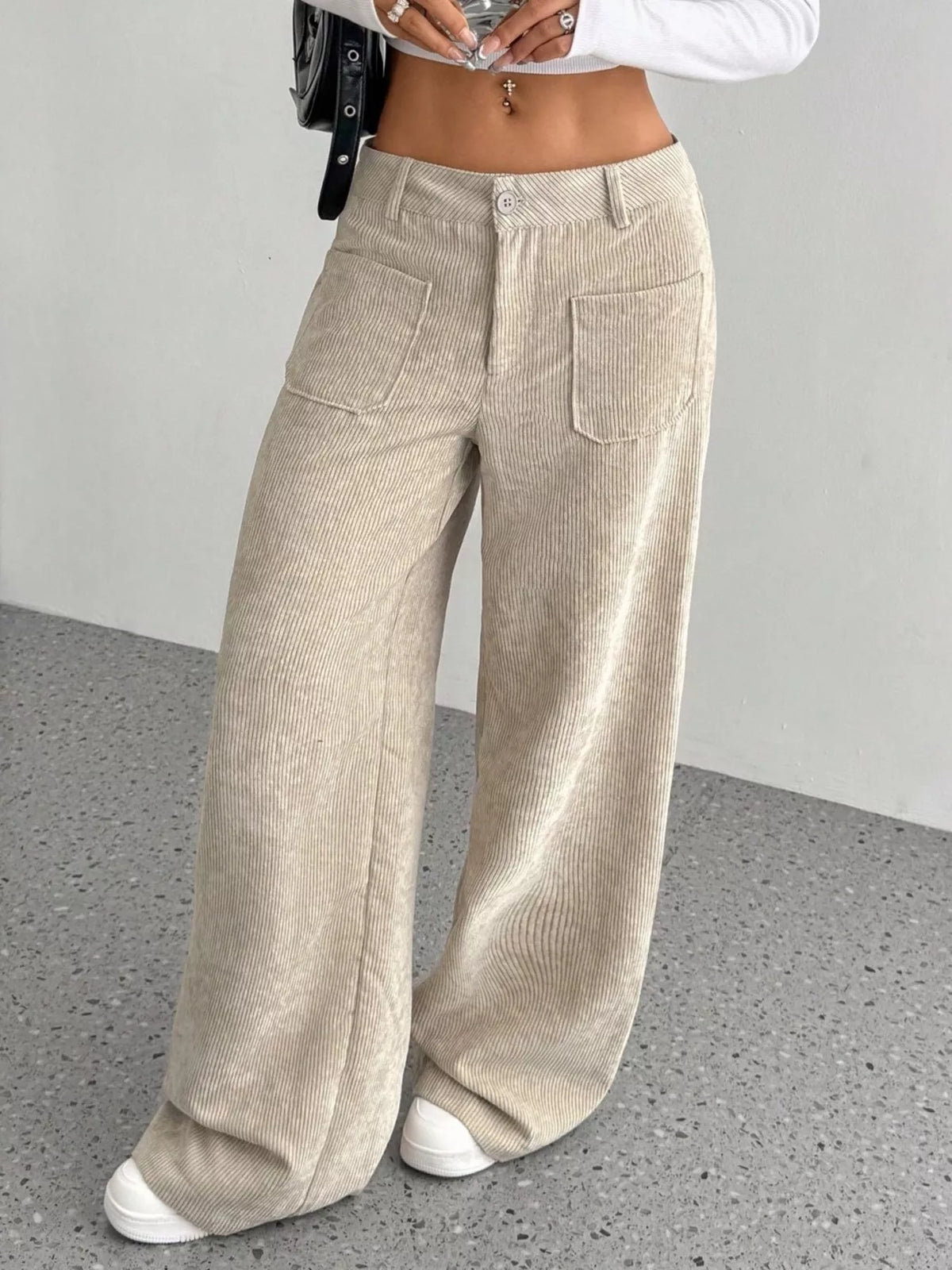 Beige stretch corduroy wide-leg pants featuring front patch pockets, a button-zip fly, and a mid-rise waist.