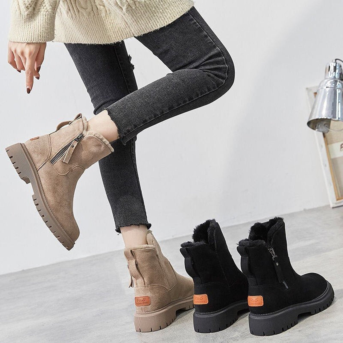 Woman in dark jeans wearing beige suede platform ankle boots, with the black colourway beside her