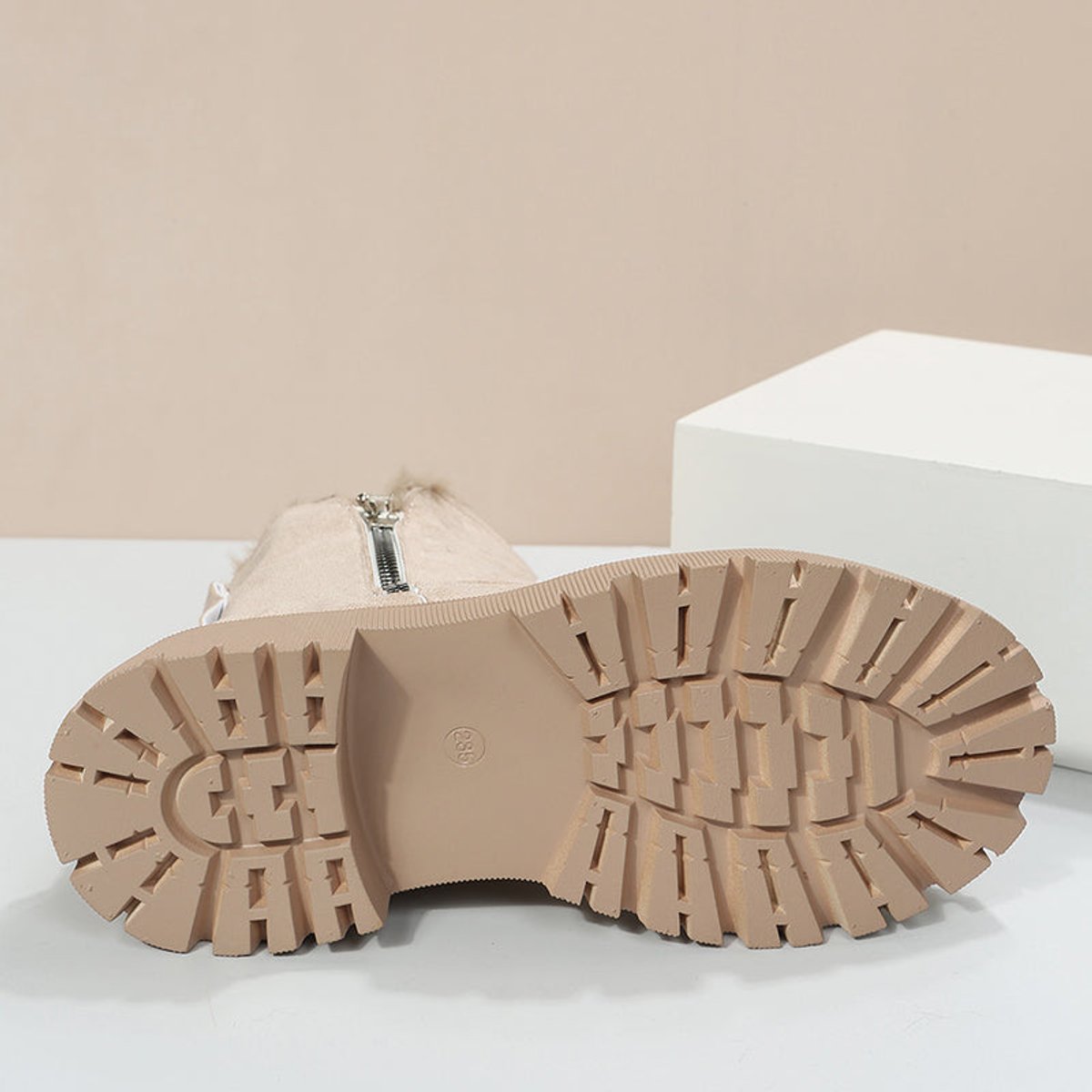 Underside of a beige suede platform ankle boot showing the deep treaded platform sole