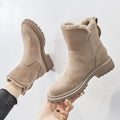 Beige suede platform ankle boots for women held up to show the fleece lining and chunky treaded sole