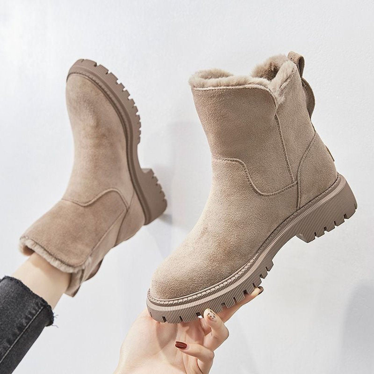 Beige suede platform ankle boots for women held up to show the fleece lining and chunky treaded sole