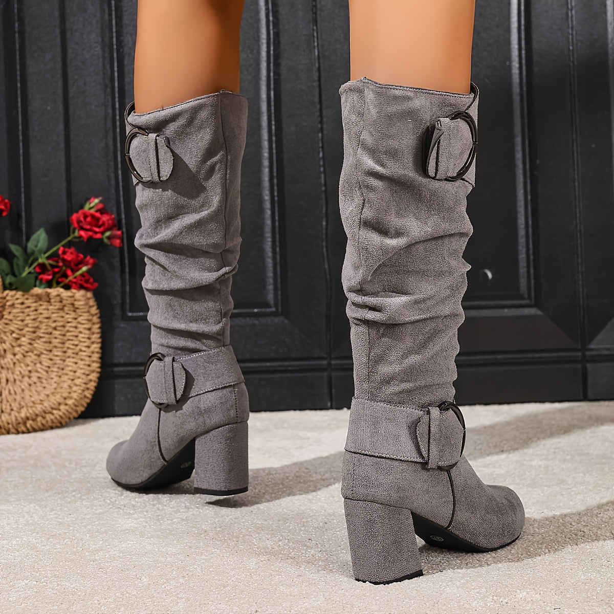 Grey suede knee-high slouch boots with ruched shafts, fold-over cuffs, twin ring buckles, and tall block heels.