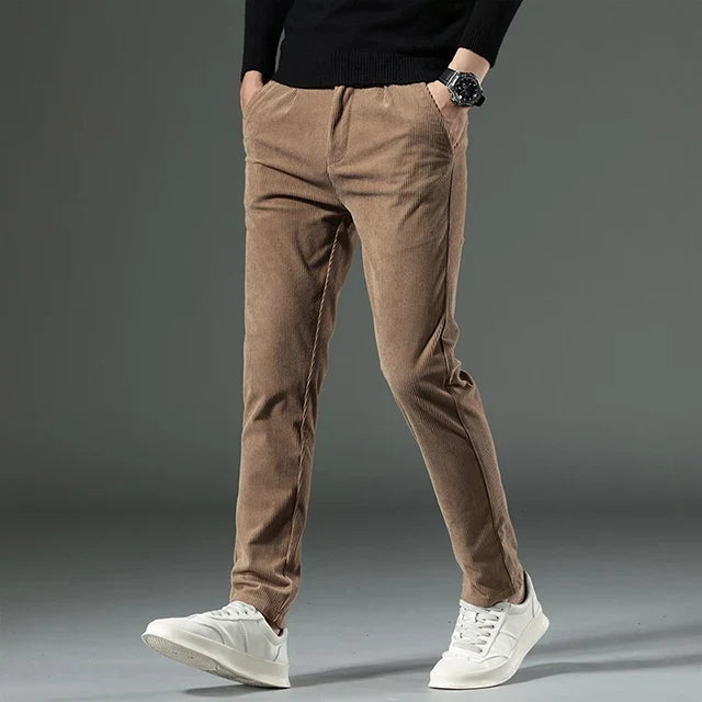 Tan heavyweight corduroy pants with a straight-leg fit, zip fly, and ribbed texture worn with white sneakers.