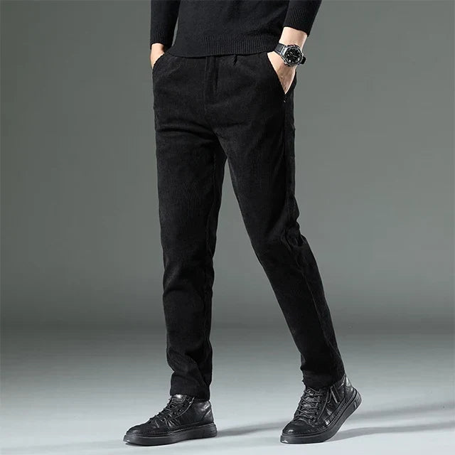 Black heavyweight corduroy pants in a straight-leg fit, featuring a clean zip-fly front and textured ribbed cotton fabric.