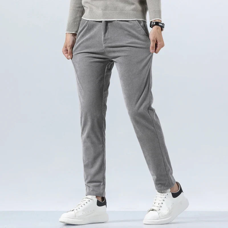 Gray heavyweight corduroy pants in a straight-leg fit with a clean zip-fly, styled with a sweater and white sneakers.