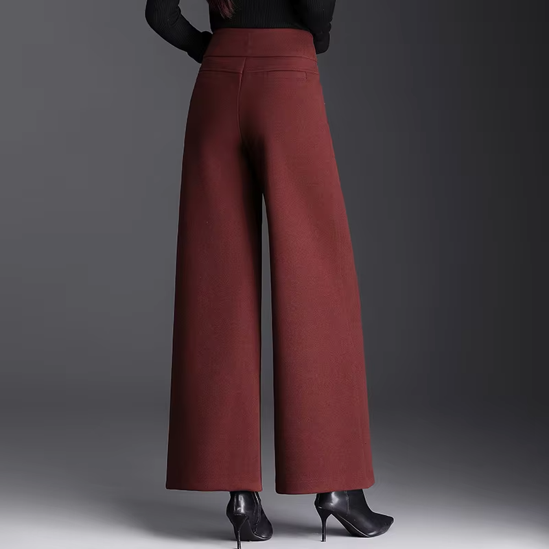 Back view of a model wearing high-waisted burgundy red wide-leg wool pants paired with black high heels.