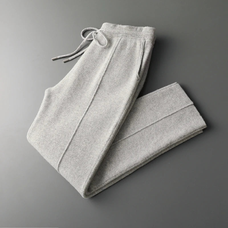Light gray wool knit trousers with a relaxed tapered fit, drawstring waist, and side pockets on a grey background.