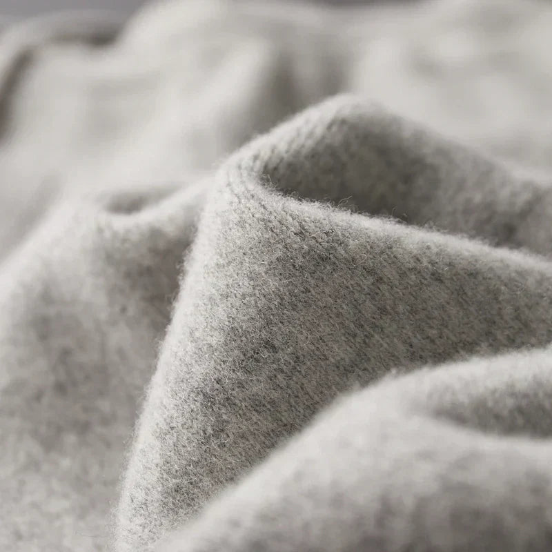 Close-up of soft, light gray wool knit fabric with a fine, textured weave and gentle folds.