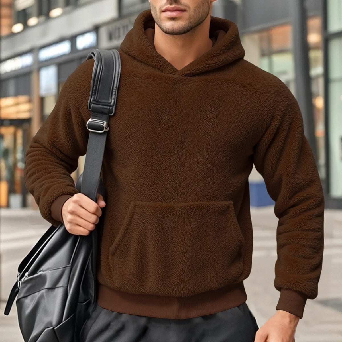 Brown teddy fleece hoodie worn by a male model, shown from the front with a shoulder bag.