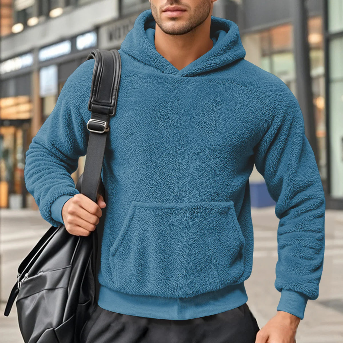 Blue teddy fleece hoodie worn by a male model, shown from the front with a shoulder bag.