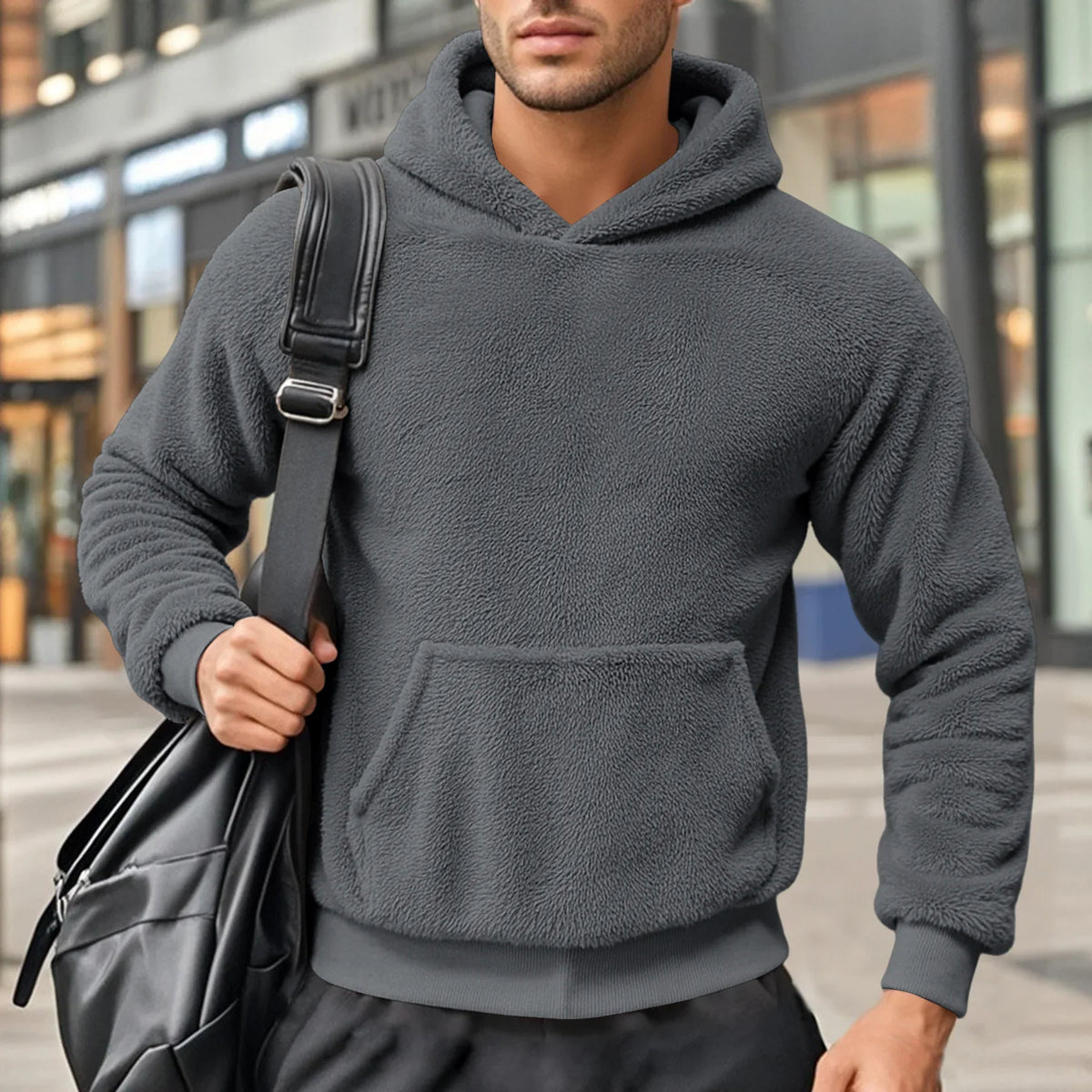 Gray teddy fleece hoodie worn by a male model, shown from the front with a a shoulder bag.